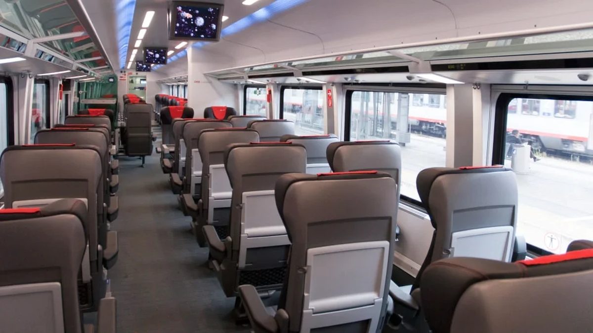Economy second-class cabin on an ÖBB Railjet Vienna to Zurich train, grey seats with red headrests and overhead screens