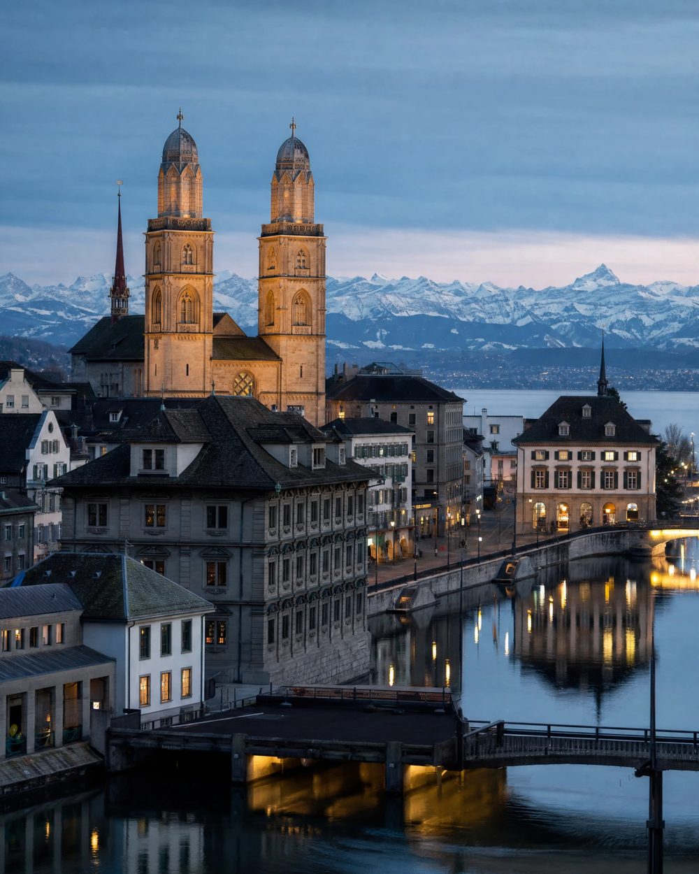 Zurich old town and the Limmat river with church towers, Swiss Alps in the distance